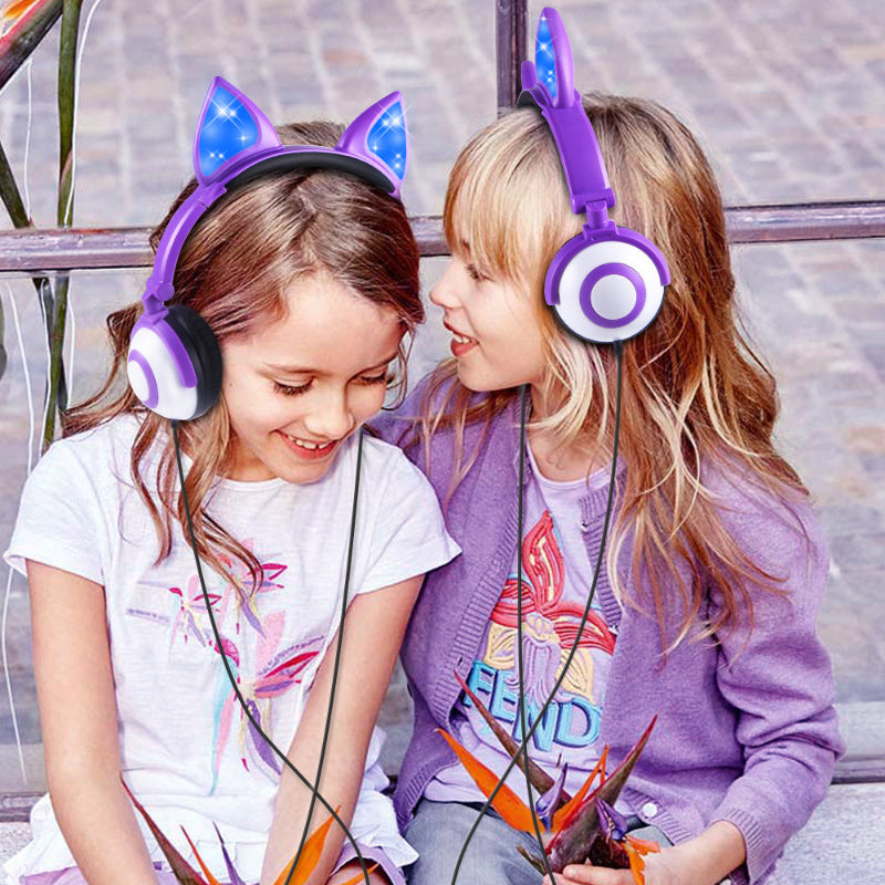 Two children wearing headphones with cat ear designs, sitting outdoors.