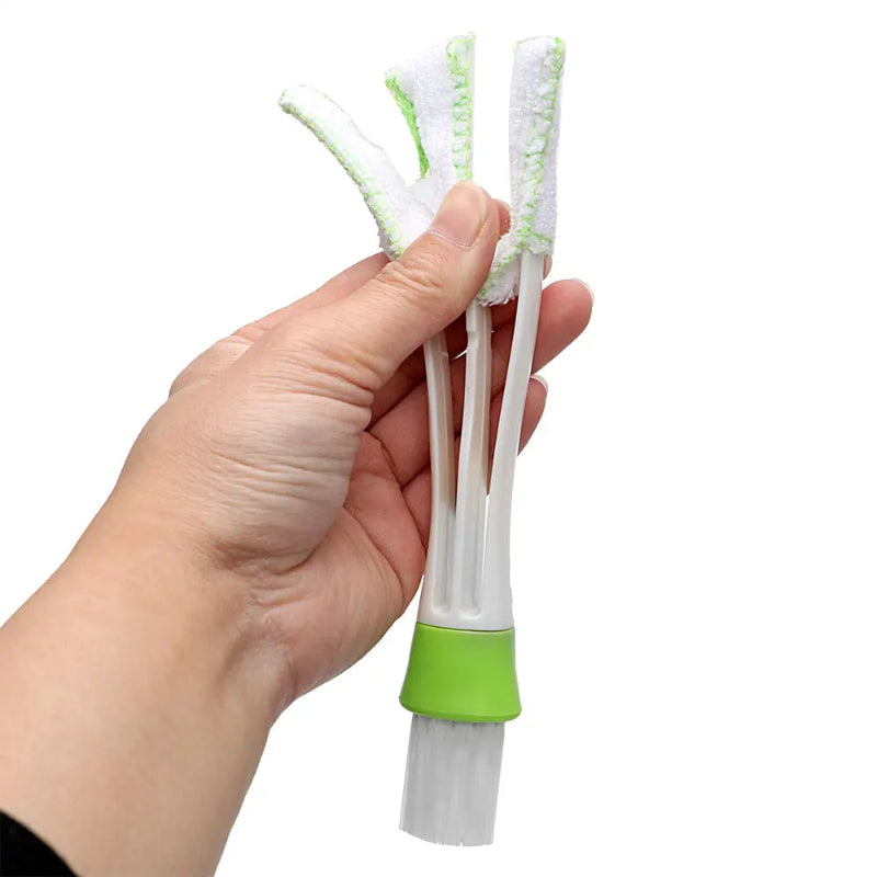 Hand holding a cleaning brush with green bristles against a white background