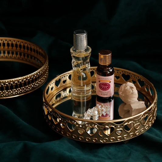 Decorative tray with perfume bottles, jewelry, and a small sculpture on a dark fabric background