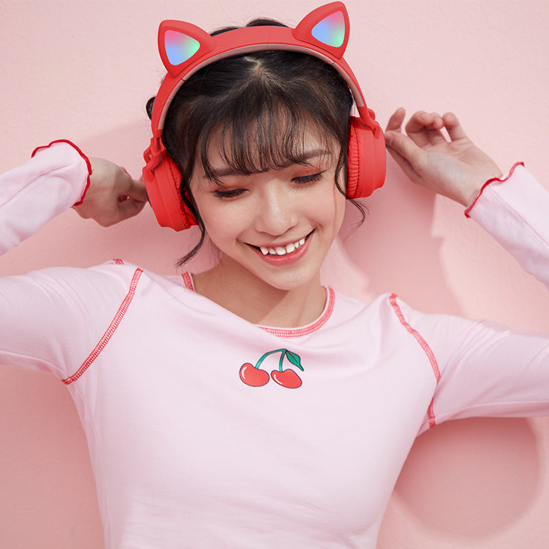 Person wearing red headphones with cat ears on a pink background