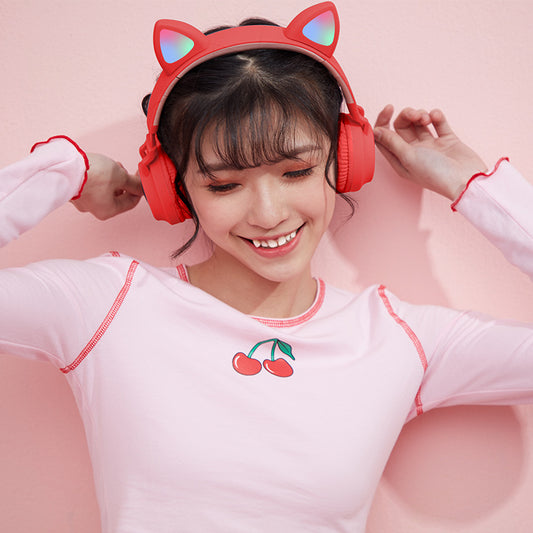 Person wearing red headphones with cat ears on a pink background