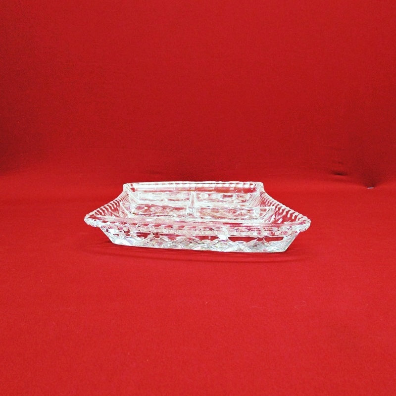 Vintage Anchor Hocking clear glass divided serving dish with a geometric pattern, displayed against a red background.