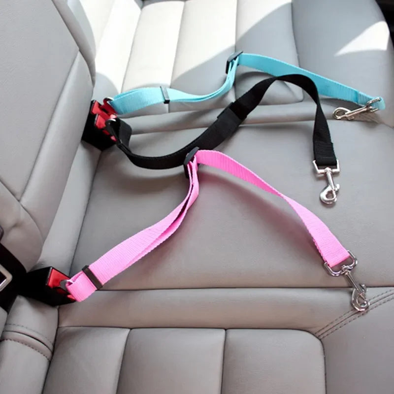 An adjustable dog seat belt leash with a metal buckle and swivel snap, displayed on a car seat. The leash is available in multiple colors including pink, black, blue, and gray.