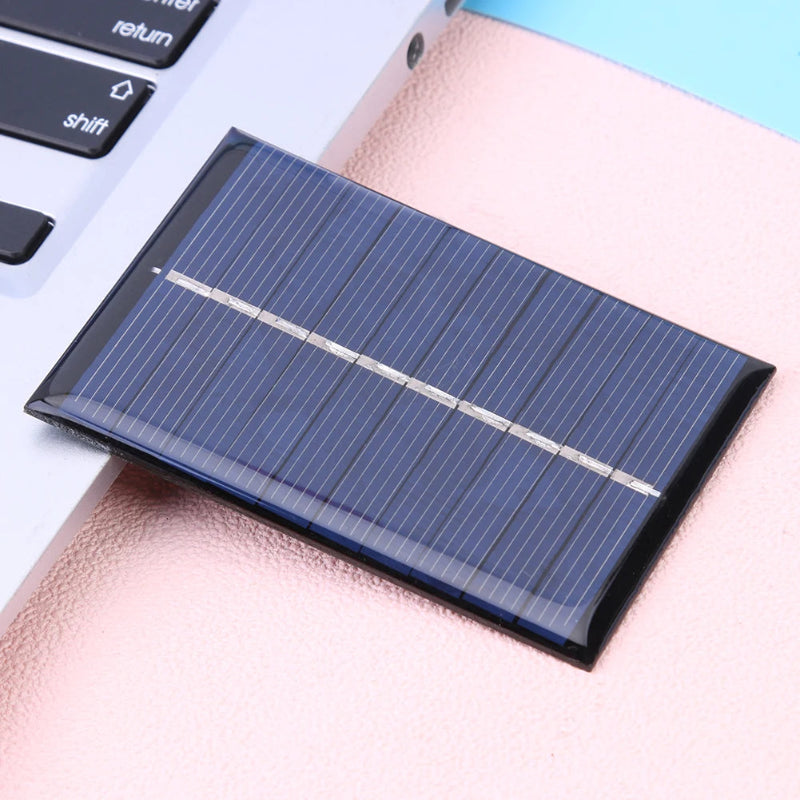 Small solar panel on a pink surface with a keyboard in the background