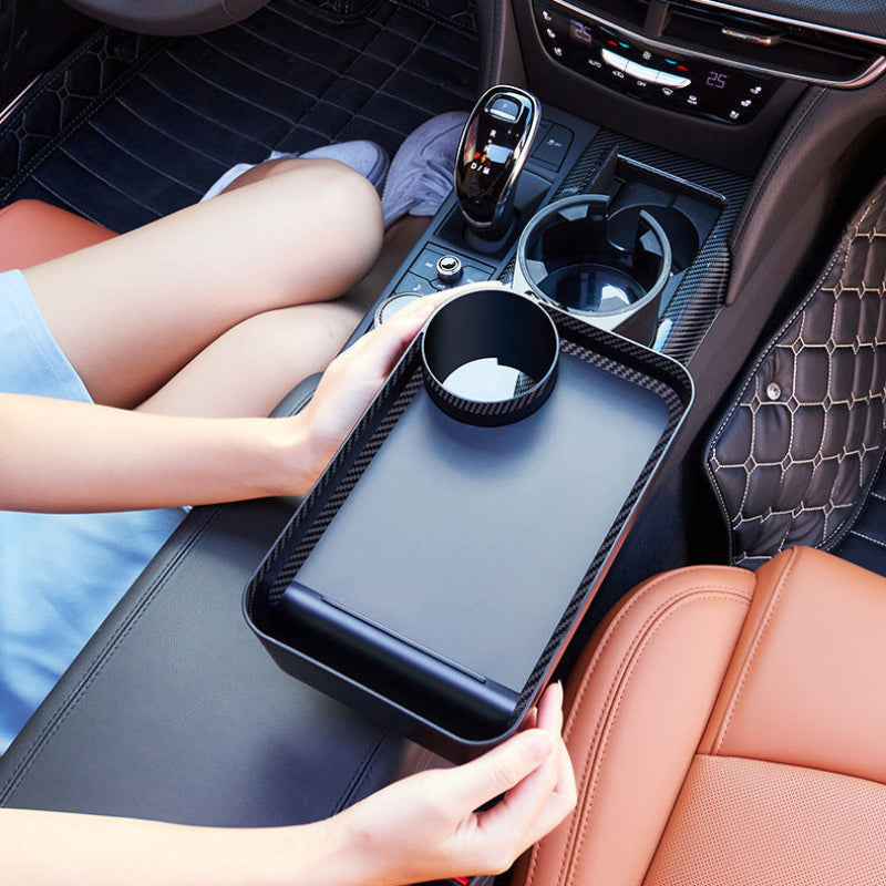 Car cup holder tray being used in a vehicle with a person's legs visible.