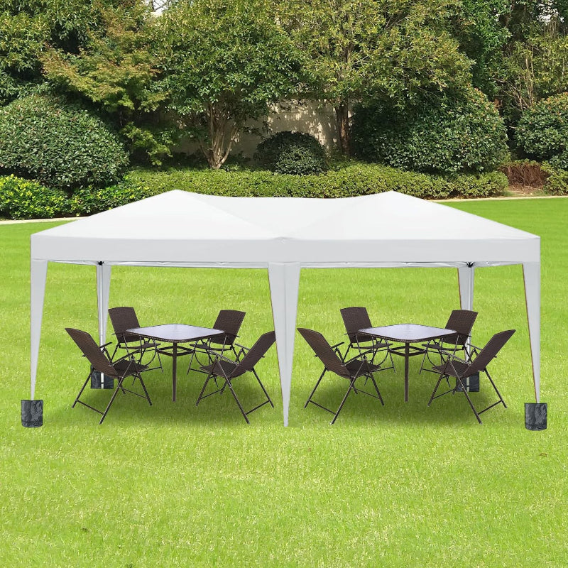 White outdoor canopy tent with tables and chairs on a grassy area with trees in the background