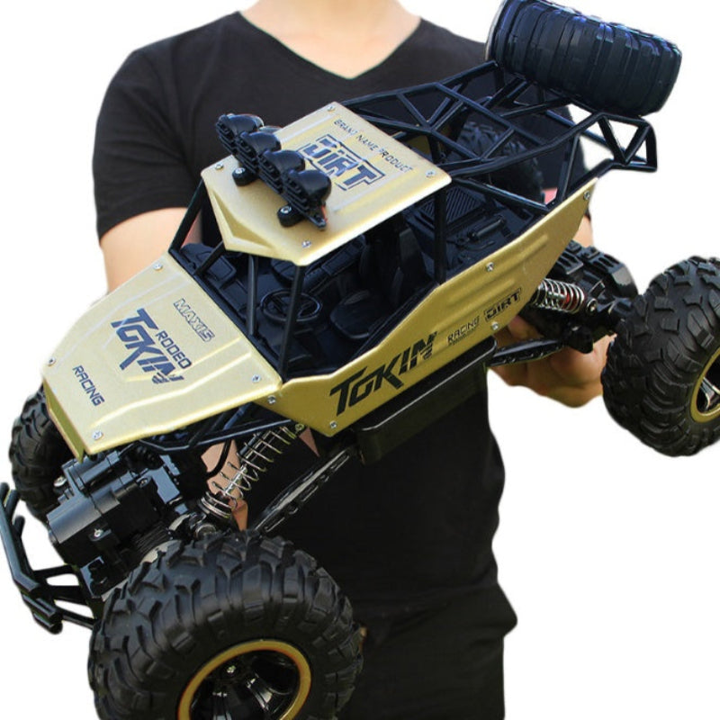 Person holding a large toy monster truck with 'TOKI' branding on a white background