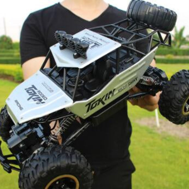 Person holding a large remote control monster truck outdoors