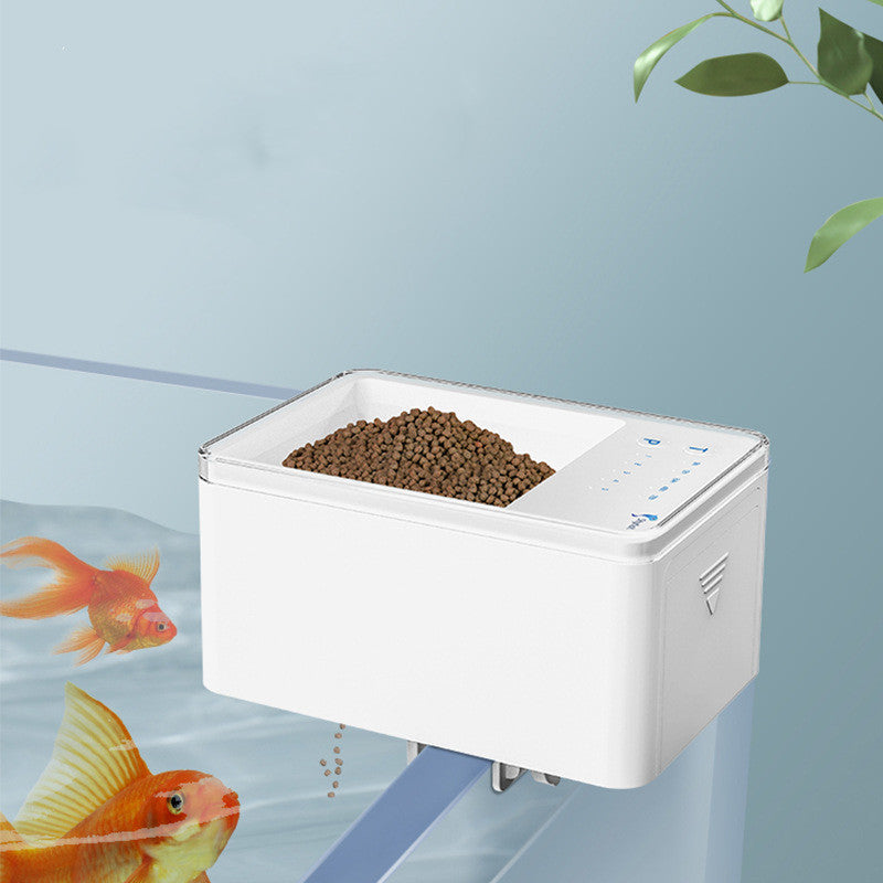 Aquarium fish feeder with fish food and goldfish in the background