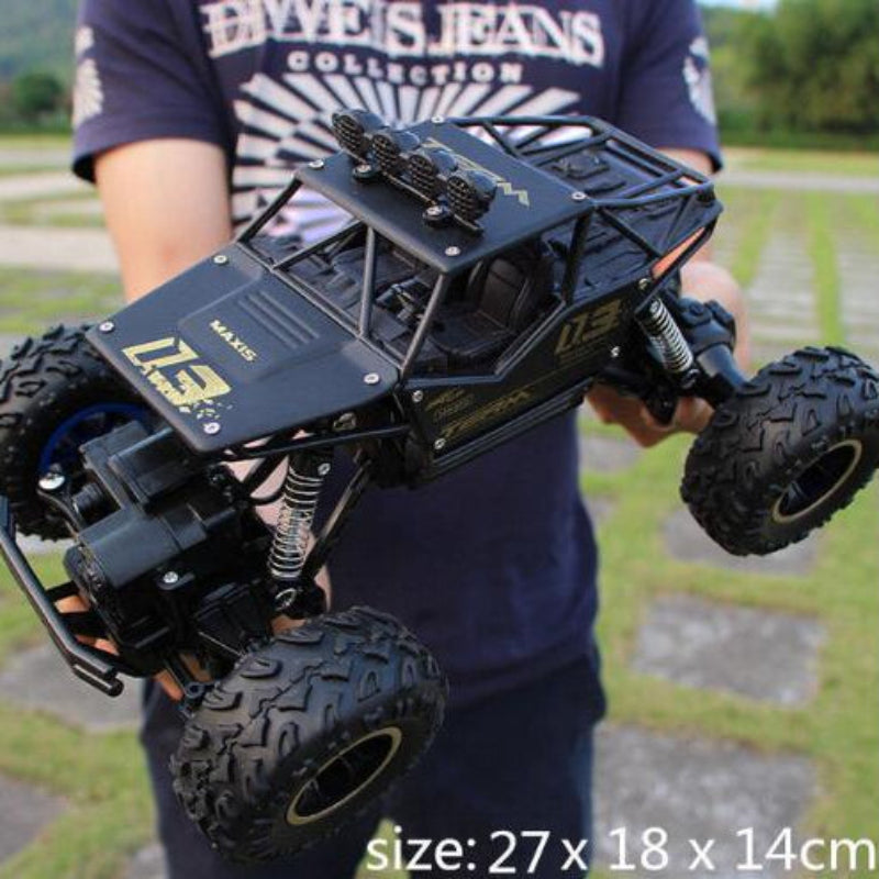 Person holding a large black RC truck with visible branding in the background