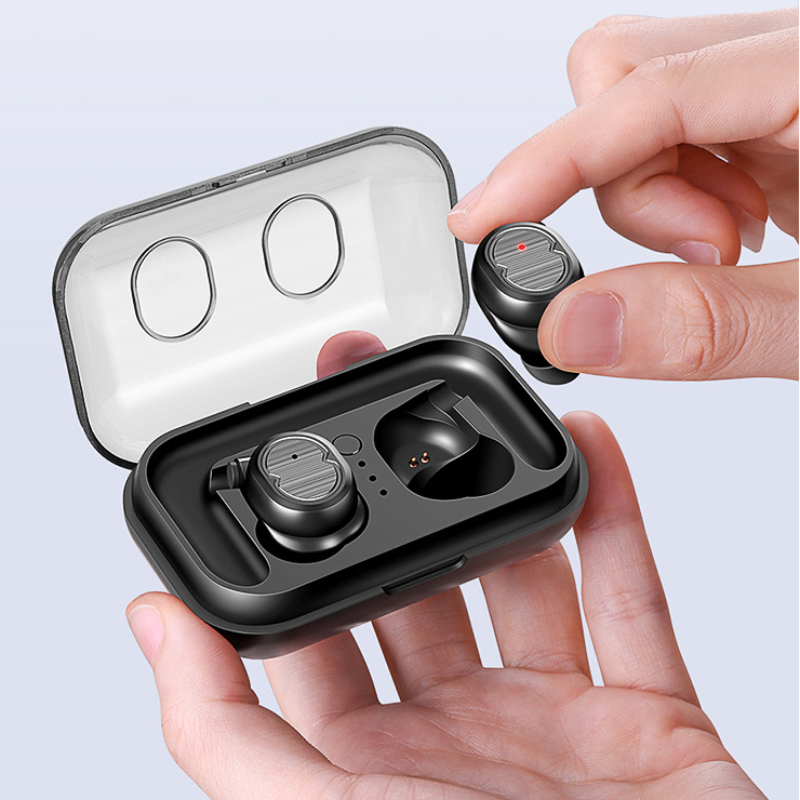 Black wireless earbuds in a transparent charging case held by a hand against a light gray background