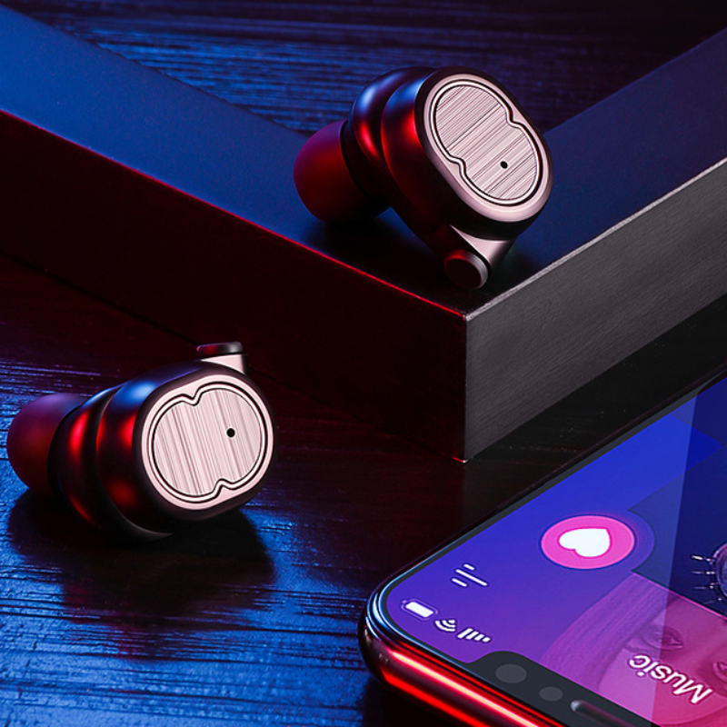 Wireless earbuds on a wooden surface with a smartphone displaying music app.