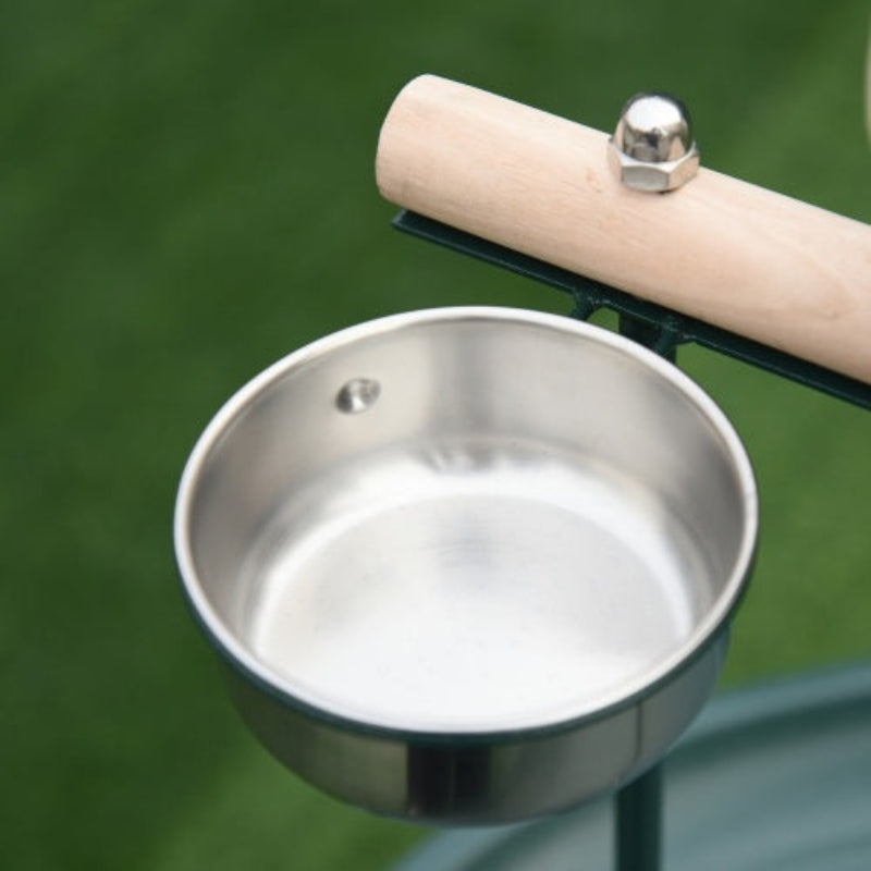 Metal bird feeder with a wooden perch on a green background