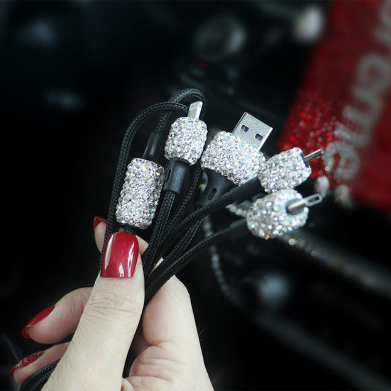 Hand holding a USB cable with decorative crystals, blurred background