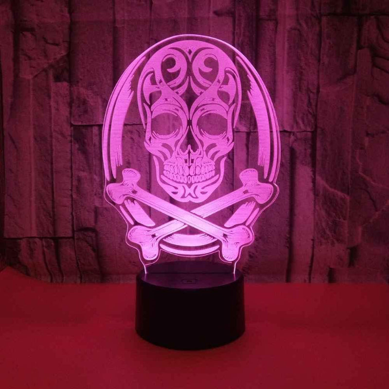 A 3D optical illusion LED night light featuring a skull and crossbones design, illuminated in a vibrant pink/magenta color, set against a dark textured background.