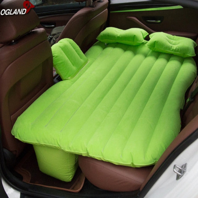 Green inflatable mattress in a car trunk with OGLAND branding.