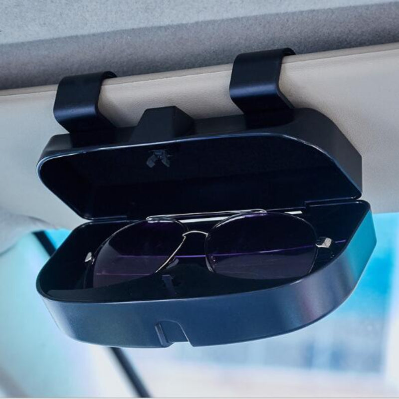 Sunglasses in a car visor holder on a car's sun visor.