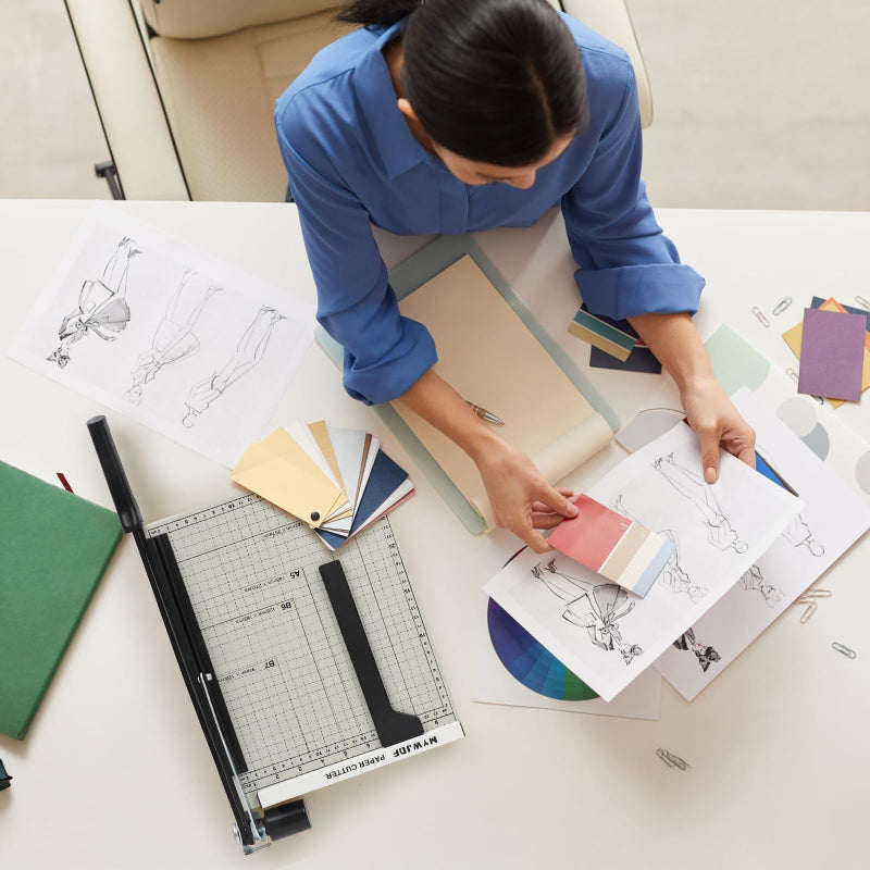 Person working on a design project with a paper cutter and color swatches.