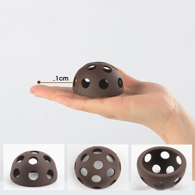 Small brown ball with holes held in a hand, showing its size with a measurement line.
