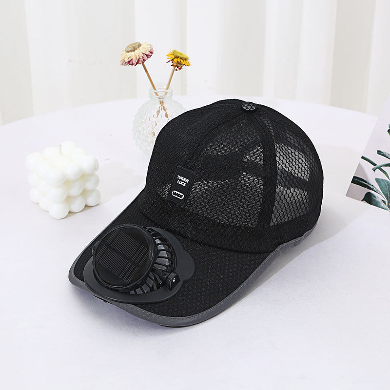 Black baseball cap with a built-in fan on a white surface with decorative elements.