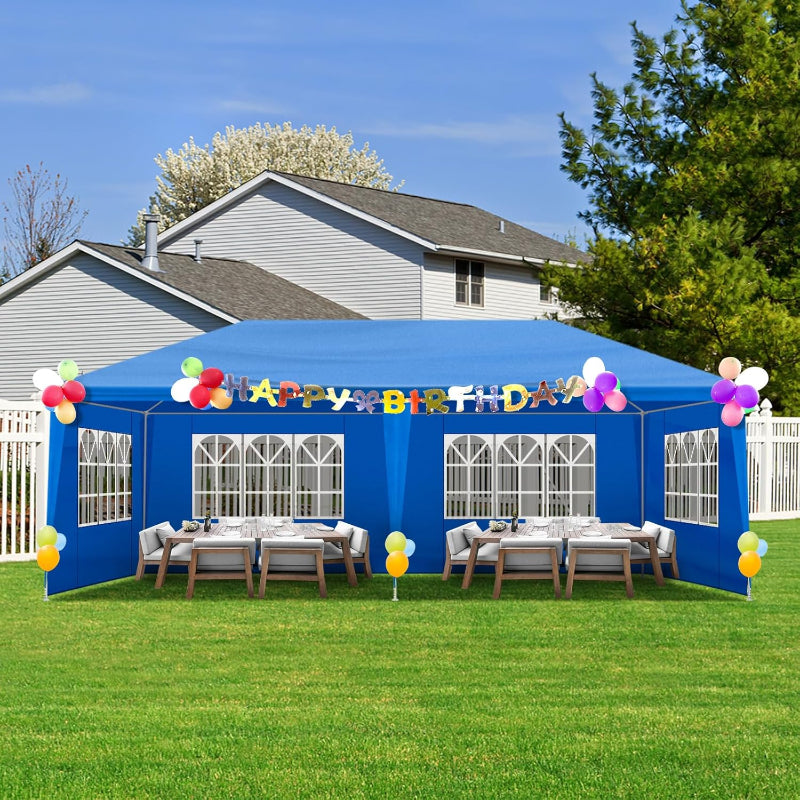 Blue party tent with 'Happy Birthday' sign and balloons in a backyard setting.