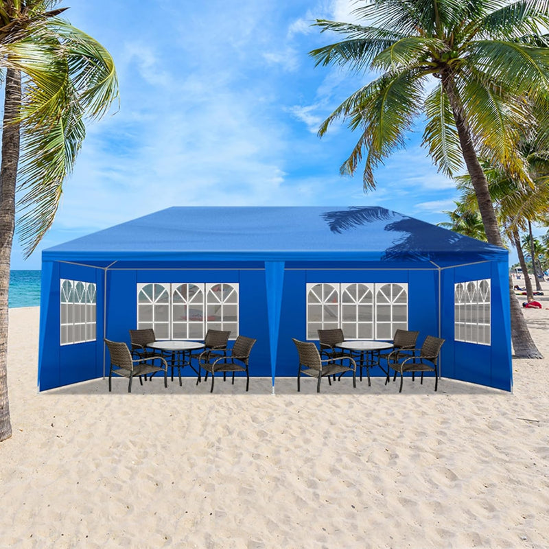 Blue outdoor canopy tent with tables and chairs on a sandy beach with palm trees.