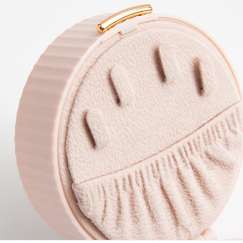 Round pink jewelry box with a gold clasp on a light gray background