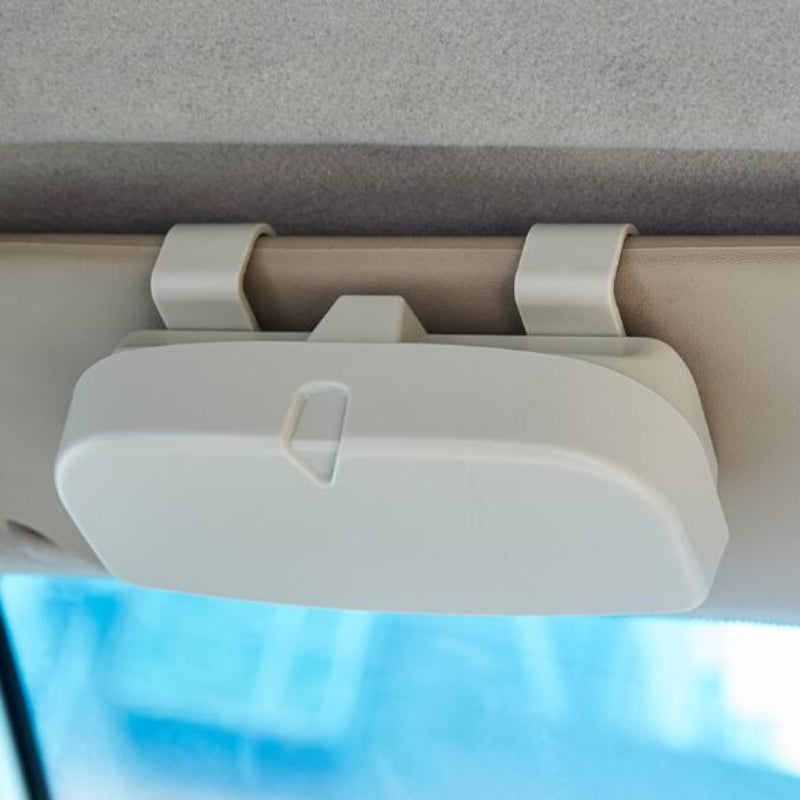 Car visor organizer mounted on a car's sun visor with a blurred blue sky background.