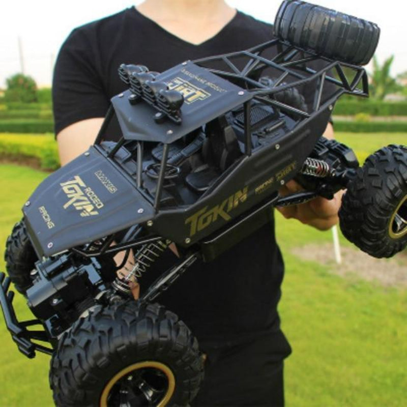 Person holding a black and gold remote control toy car with 'Tokin' branding in an outdoor setting.