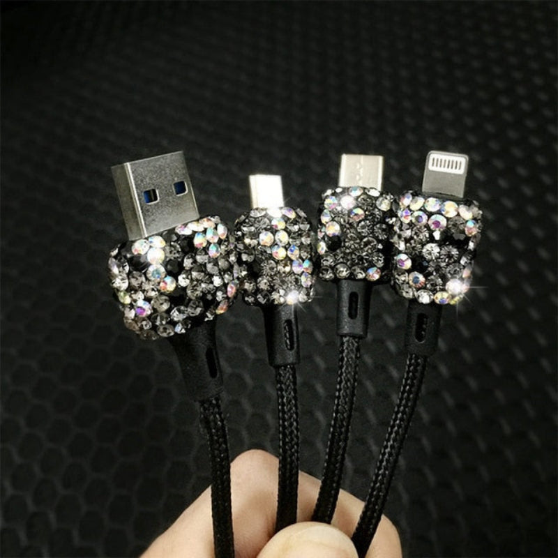 Three rhinestone-encrusted USB cables held against a textured black background