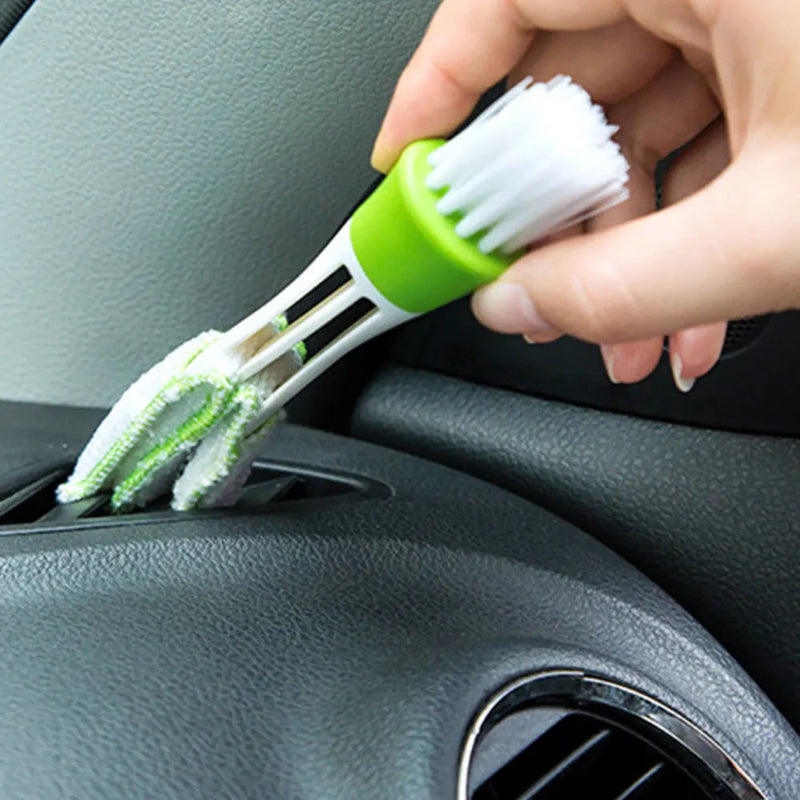 Hand using a car cleaning brush to clean a car's dashboard.