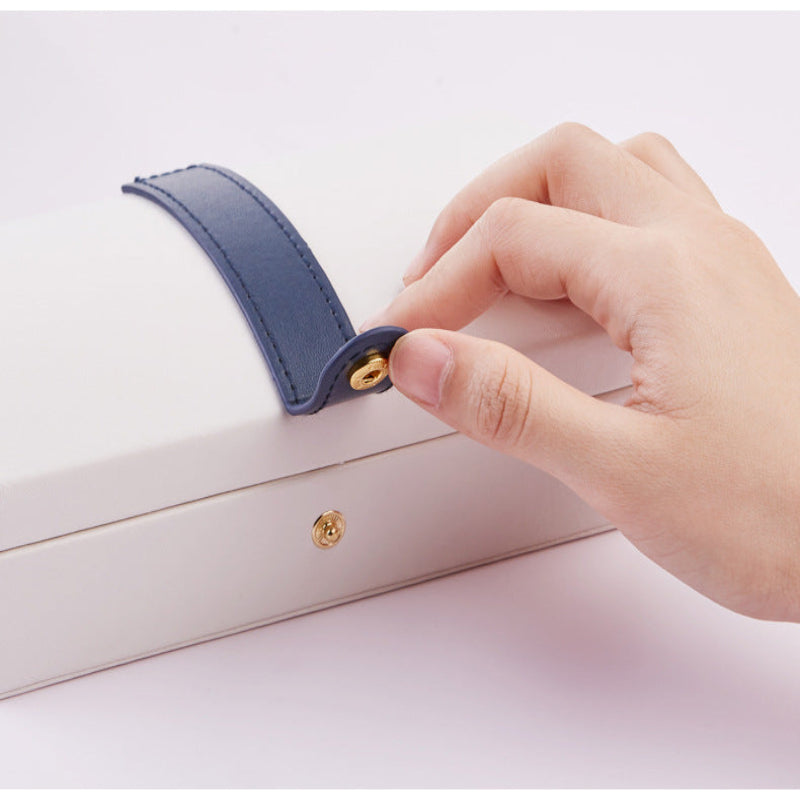 Hand closing a small white box with a blue handle on a light pink background