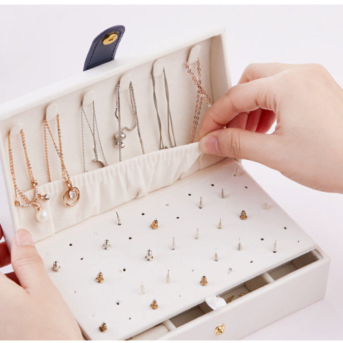 Jewelry organizer with necklaces and earrings, being held by a person.