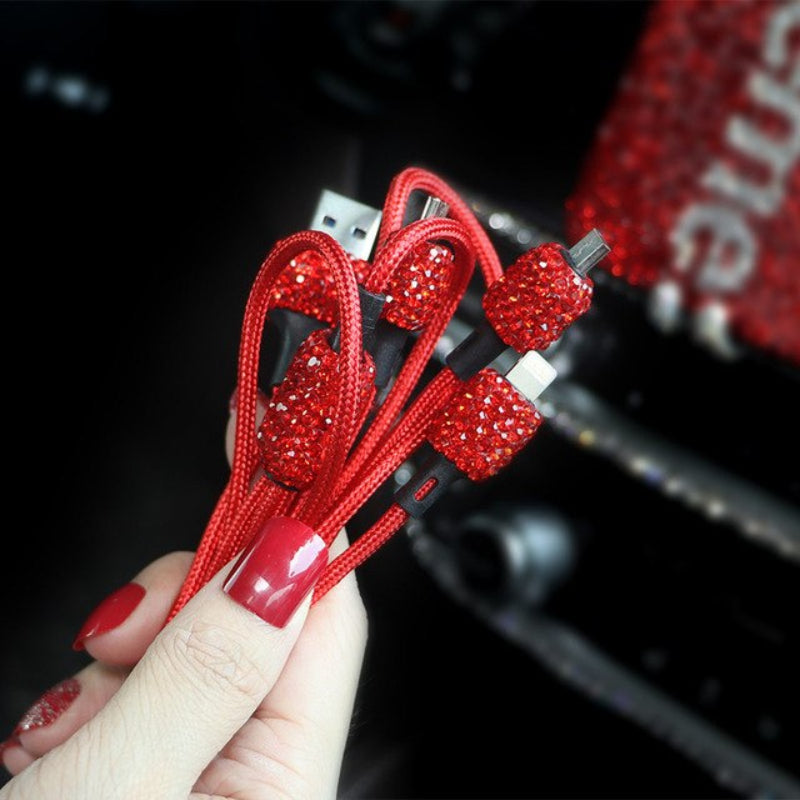 Red rhinestone-laden earbud cables held by a hand with red nail polish.