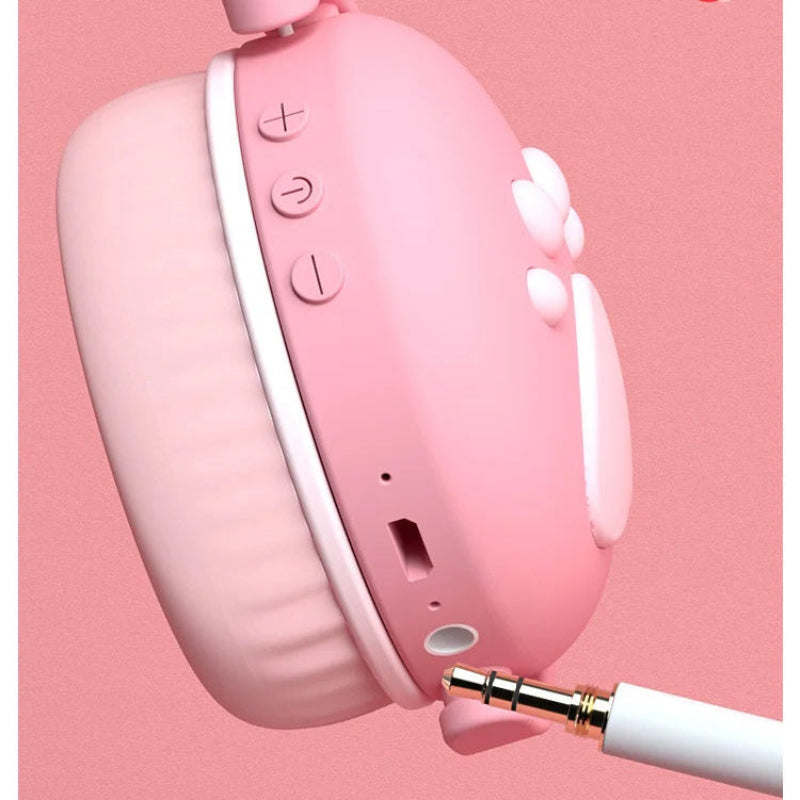 Pink Bluetooth headphones with a 3.5mm AUX cable on a pink background