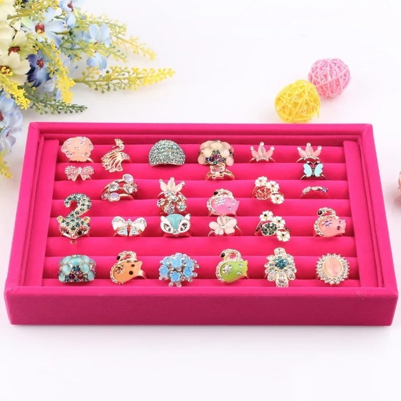 Pink jewelry display box with various small rings on a white background