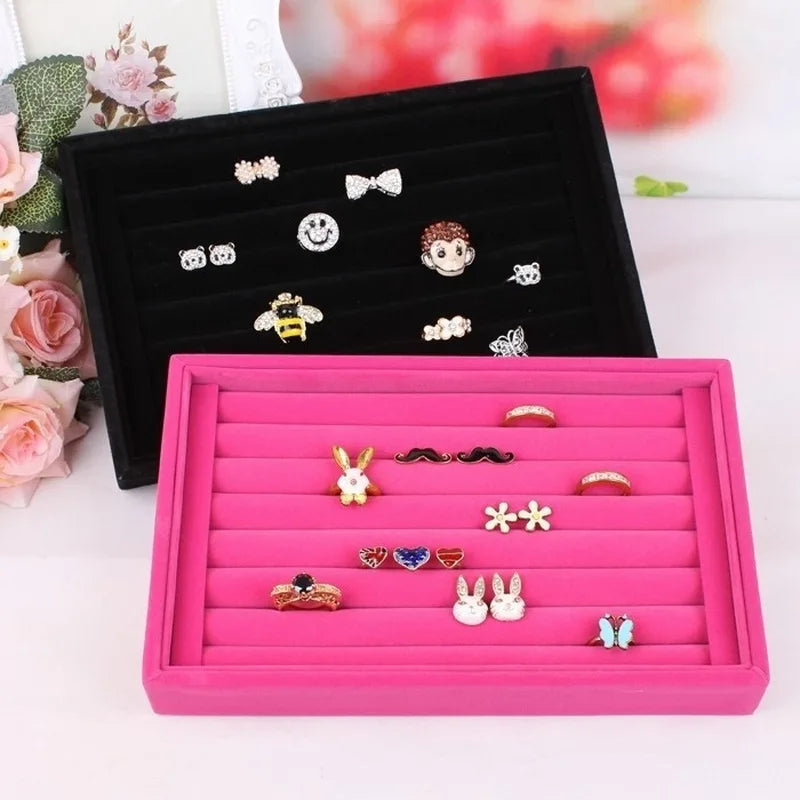 Pink and black jewelry trays with various earrings on a light background
