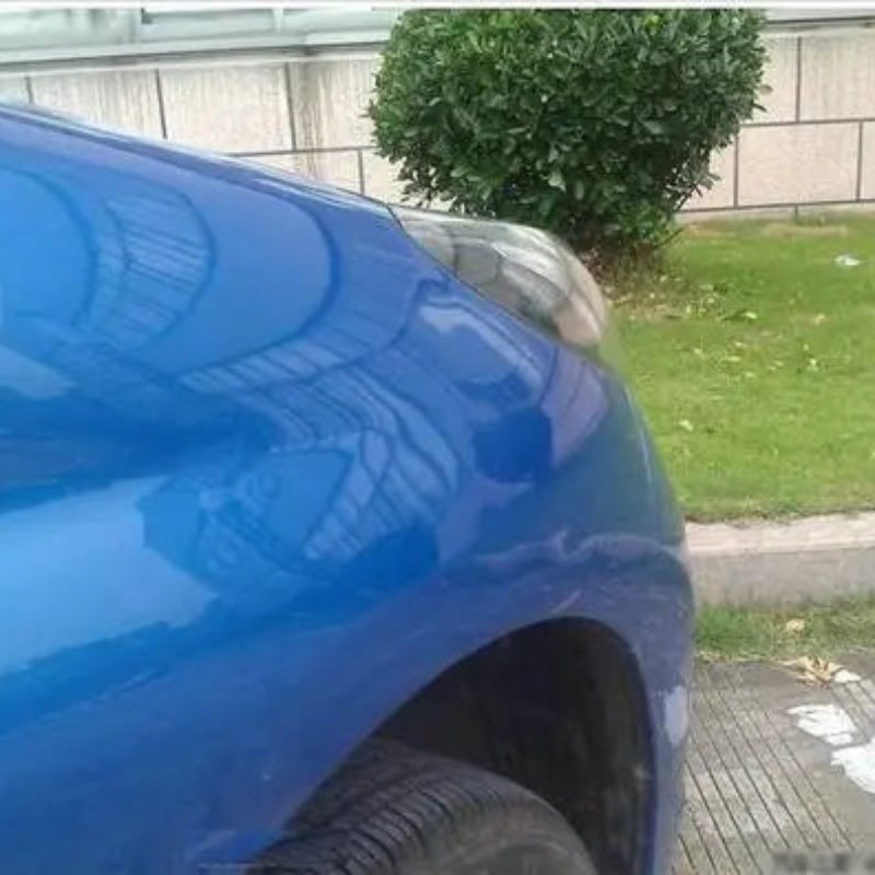 Blue car with a dent on its side, parked outdoors.