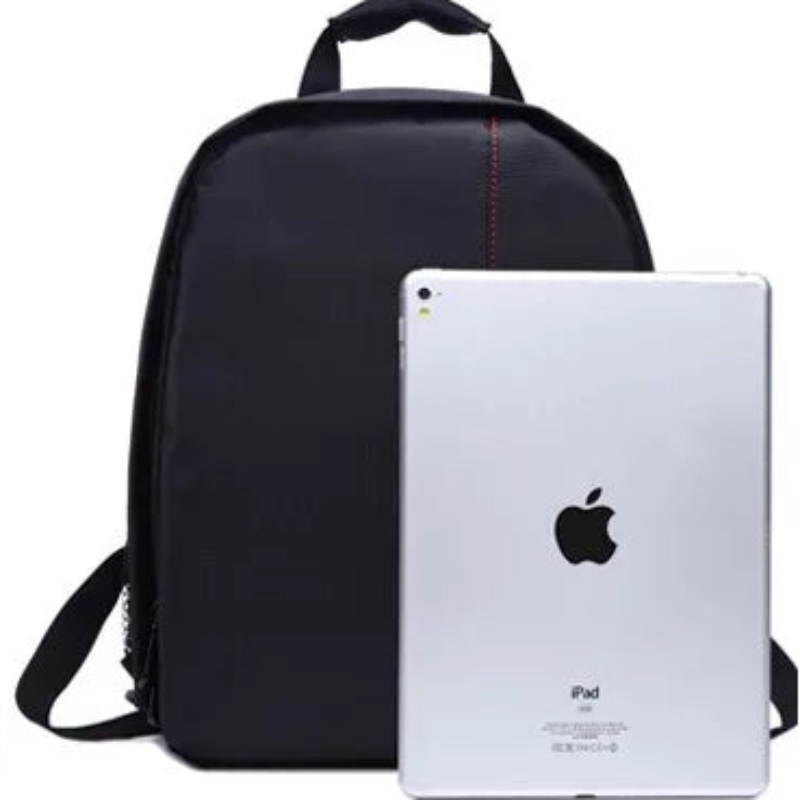 Black backpack next to a white Apple iPad on a white background