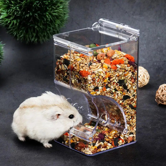 Clear pet feeder with food and a small white animal interacting with it on a dark background