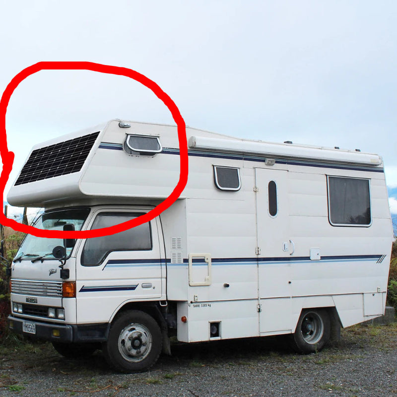 White camper van with solar panel on roof against a clear sky