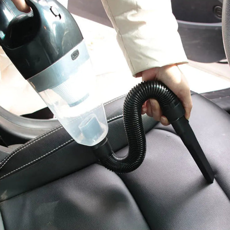 Person using a handheld vacuum cleaner to clean car seats.