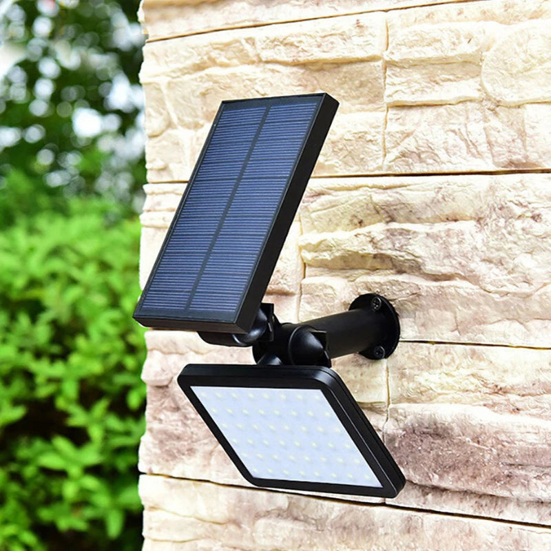 Solar-powered outdoor light fixture attached to a stone wall with greenery in the background.