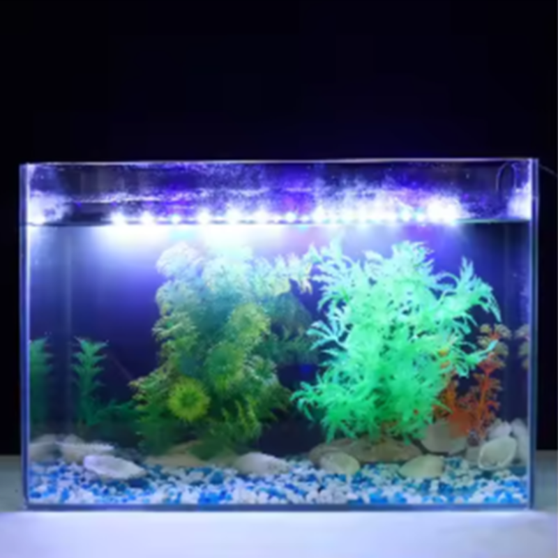 Small aquarium with LED lights, plants, and rocks on a dark background