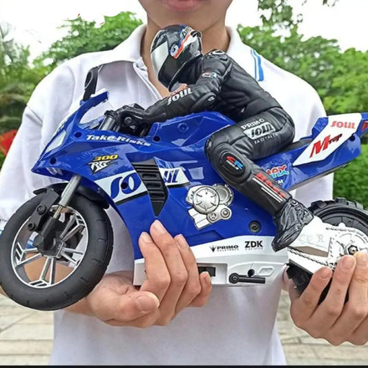 A person holding a blue remote-controlled motorcycle toy with a figurine rider wearing a black and white suit.