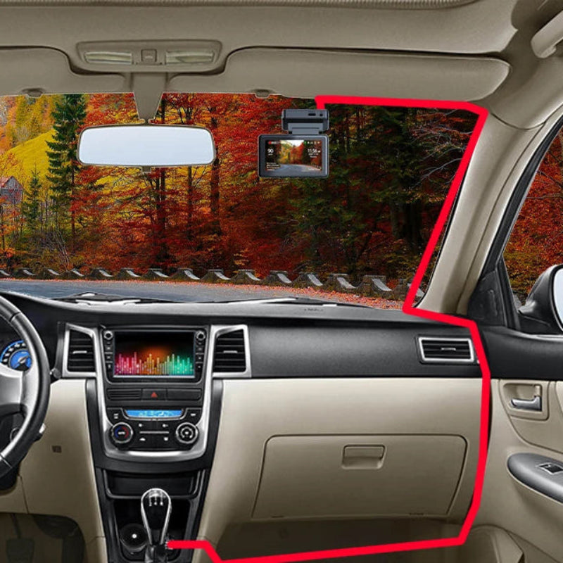 Car interior with a sun visor and windshield view of a forest.
