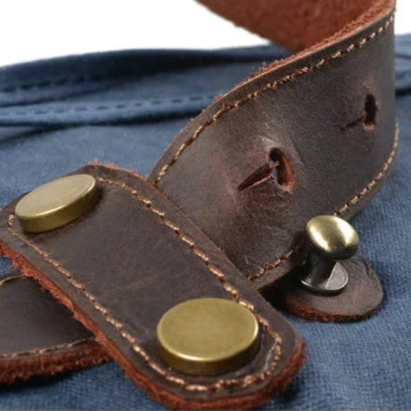 Close-up of a brown leather strap with gold buckles on a blue fabric background
