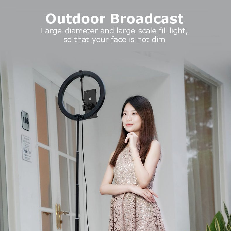 Woman standing next to a large outdoor broadcast light in a bright room.