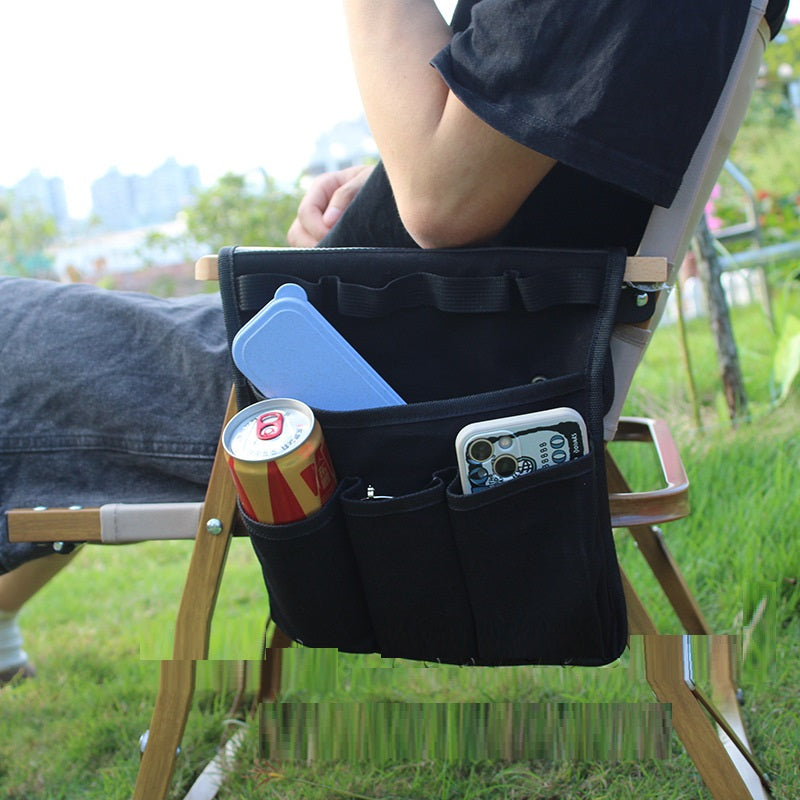 Person sitting on a chair with a black organizer holding a can and phone, outdoors.