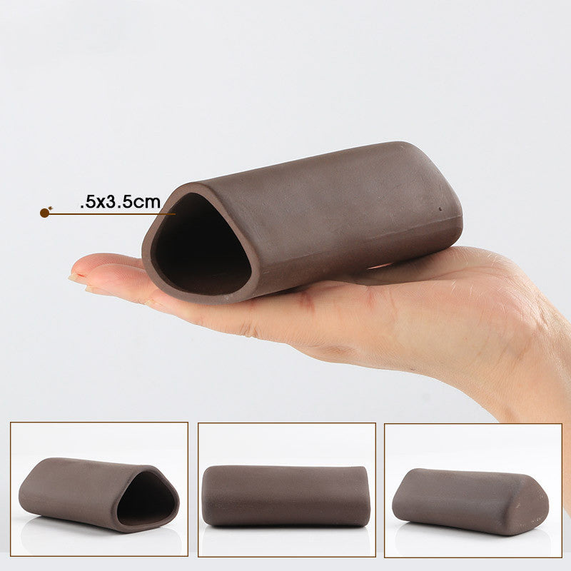 Brown cylindrical object held in a hand with measurements, on a light gray background